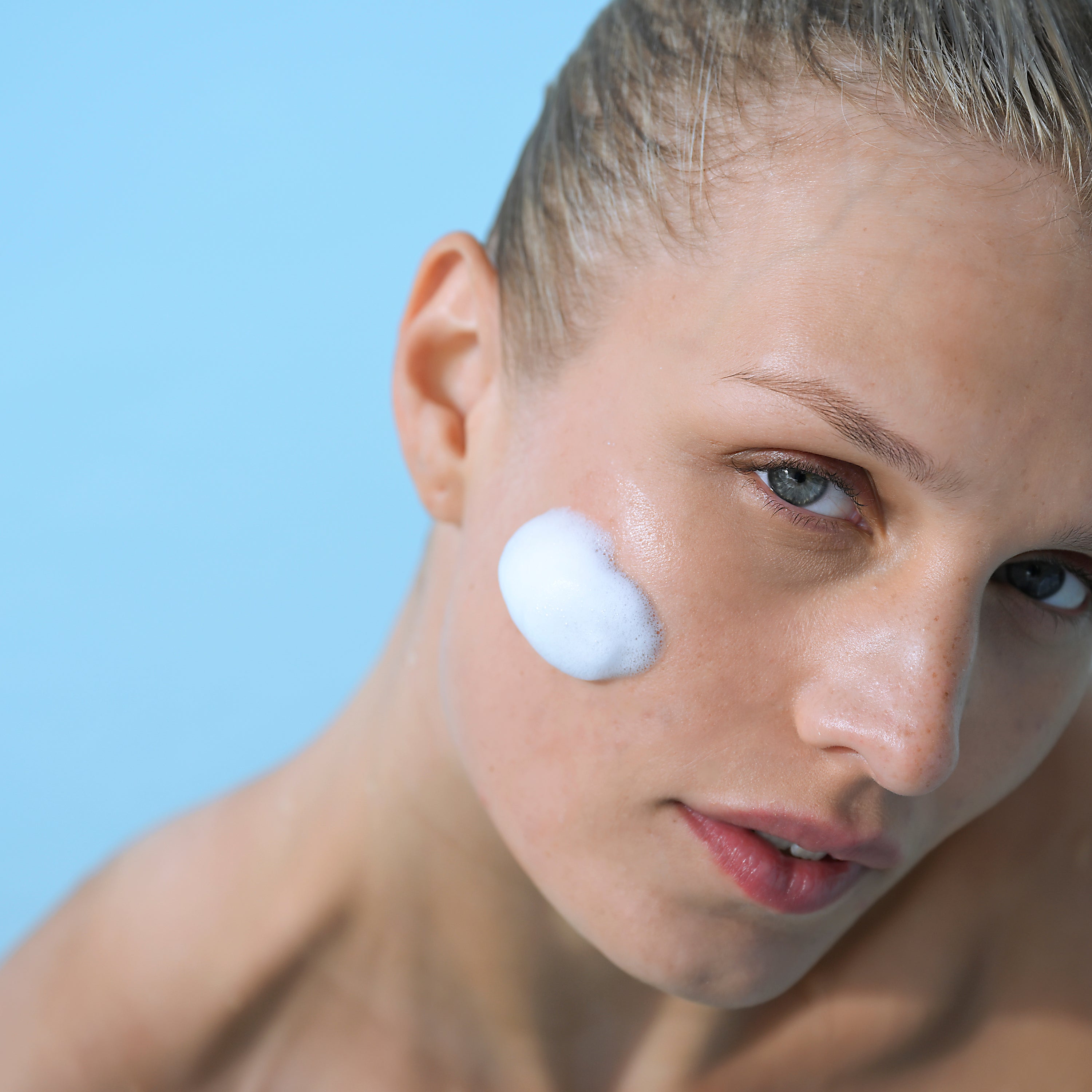 Model applying Foaming Cleanser foam to cheek