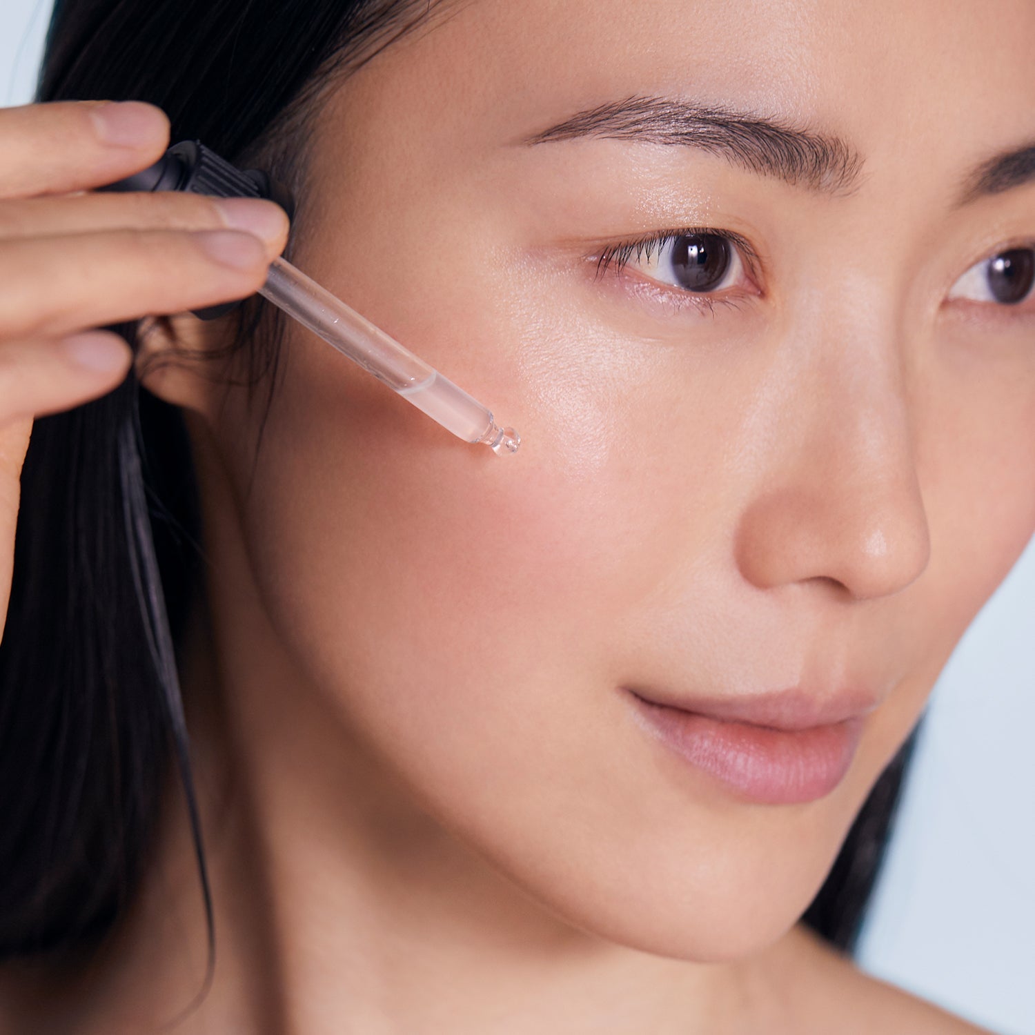 Model applying BL+ The Serum to face using dropper