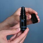 Hand holding BL+ Eye Serum with metal roller applicator and removed cap