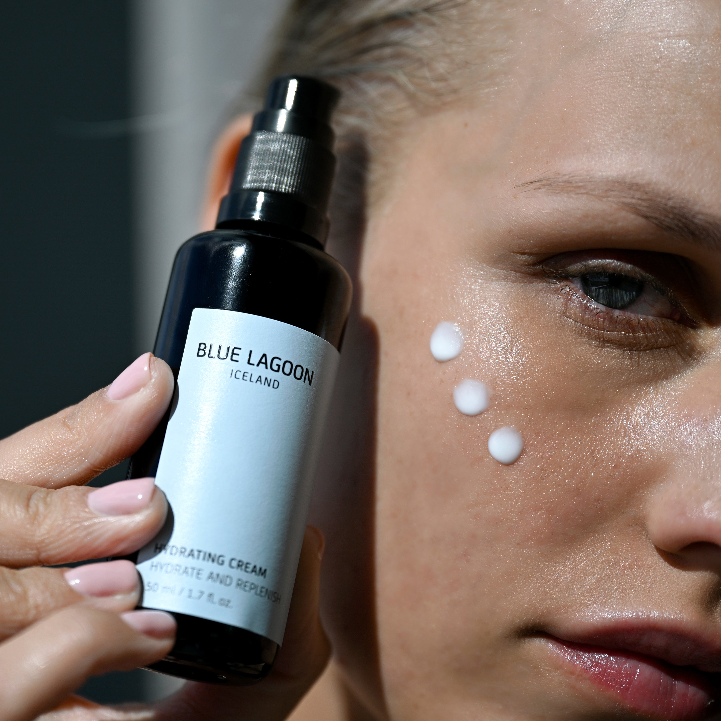 Model applying Hydrating Cream to cheek from pump bottle