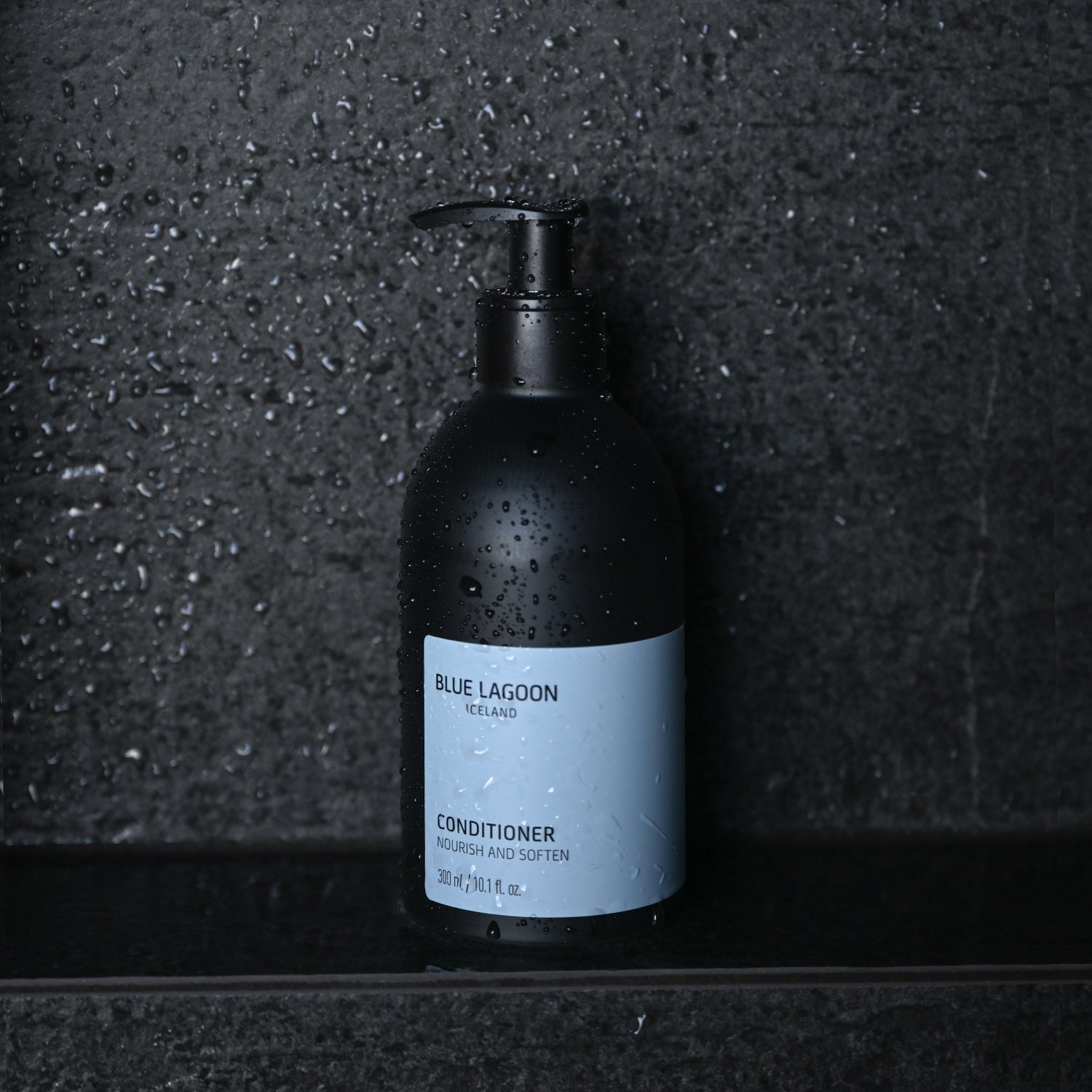 Conditioner bottle standing on wet stone surface in shower setting