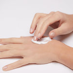 Model applying Mineral Intensive Cream to the back of the hand, showing creamy texture and spreadability
